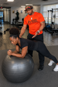 elson teaching a woman to use exercise ball